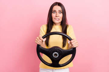 Poster - Photo of doubtful unsure woman dressed yellow t-shirt biting lip riding vehicle isolated pink color background