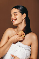 Wall Mural - Self-pampering time: Young woman smiles as she brushes her hair after a bath