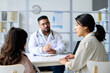 © AnnaStills - Young woman with child discussing treatment with doctor during their visit to clinic