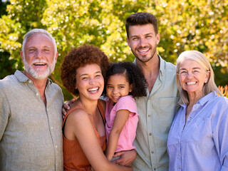 Portrait Of Multi-Generation Family Standing In Garden Smiling At Camera