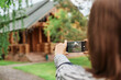 © sementsova321 - Back view of brown haired woman photographing wooden house in part vising new places sightseeing traveling having vacation shooting video for her travel blog.