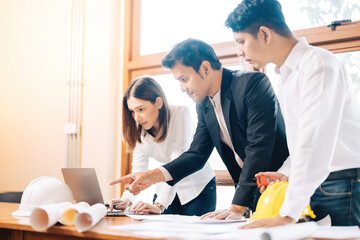 Wall Mural - A team of 3 male and female architects look like engineers. Designing a project design through a tablet in the office About the construction business industry. There is a blueprint. Safety helmet.