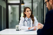 © bnenin - A caring female doctor talking with a male patient in the examination room.