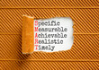 SMART symbol. Concept words SMART specific measurable achievable realistic timely on white paper. Beautiful brown background. Business SMART specific measurable achievable realistic timely concept.
