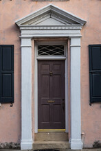 A Colonial Style Front Door With An Eccentric Door Frame In Sunlight.