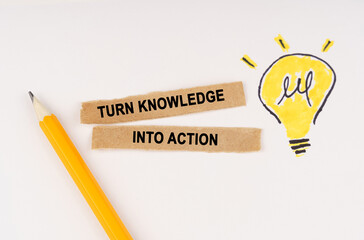 On a white surface, a luminous light bulb and pieces of paper with the inscription - turn knowledge into action