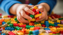 Close-up Photograph Of A Little Kid's Hands As Joyfully Plays With A Colorful Set Of Building Blocks.
