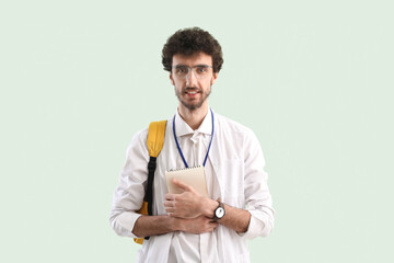 Canvas Print - Male student with notebook on green background