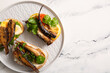 Plate of tasty sandwiches with canned smoked sprats on white marble background