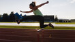 Young overweight woman running and jumping over hurdles on an athletics track on a sunny summer day