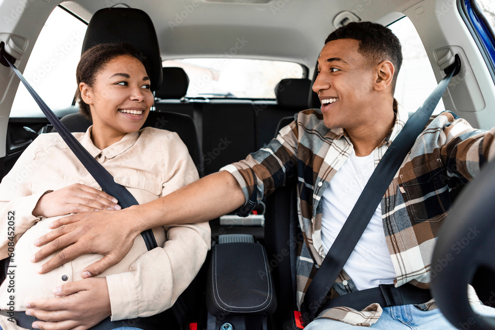 Happy african american husband and his pregnant wife driving in car ...