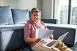 © Baba Images - Latin middle aged man going over his home finances and using a laptop