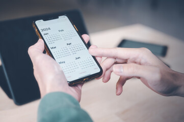 Concept of time management financial planning and reminder for 2024. man using smartphone working with calendar 2024, business planning marketing and investment, schedule appointment meeting