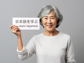 Wall Mural - A Japanese female teacher hold card with text Learn Japanese in English and Japanese languages. Generative AI.