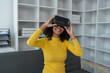 © Phimwilai - Stylish cheerful african american woman in vr headset spread arms and smiling while dancing and raising fingers in cyberspace. Metaverse vr future girl concept.