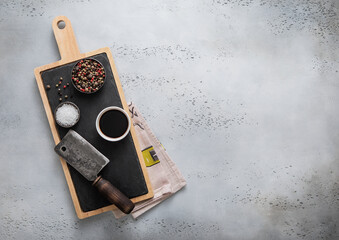 Wall Mural - Meat cleaver on stone cutting board with salt and pepper on light background.