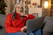 Long-haired pretty senior woman in eyeglasses with a laptop