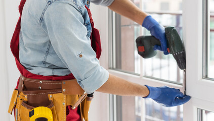 master with a screwdriver sets fittings on the window