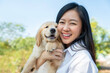 Young Asian woman holding Golden Retriever puppy in outdoors. Owners look like their dogs. Love pets concept.