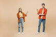 © ViDi Studio - Full body fun young couple two friends family man woman wear casual clothes together point index finger between them on workspace area mock up isolated on pastel plain beige color background studio.