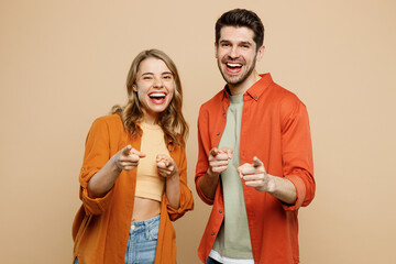 Young fun couple two friends family man woman wear casual clothes point index finger camera on you motivating encourage together isolated on pastel plain light beige color background studio portrait.