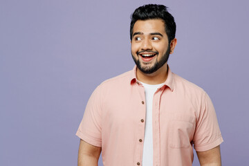 Wall Mural - Young smiling happy Indian man wear pink shirt white t-shirt casual clothes looking aside on workspace area mock up isolated on plain pastel light purple background studio portrait. Lifestyle concept.