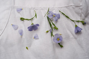white linen shirt, close-up, fabric folds and seams with blue linen flower