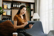 © Nuttapong punna - Asian businesswoman working in home office with working notepad, tablet and laptop documents  on sofa in living room