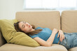 © Chanakon - Asian caucasian woman lying on comfortable sofa in living room. Asian female fall asleep take a nap. Exhausted tired young woman. Cozy couch breath fresh air inside modern living room Leisure