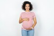 © Roquillo - Beautiful pregnant woman wearing striped T-shirt standing over white studio background with a happy and cool smile on face. Lucky person.