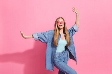 Photo portrait of attractive young teenager woman raise hands dance have fun wear trendy jeans clothes isolated on pink color background
