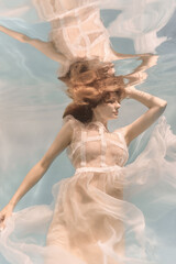 Wall Mural - Portrait of a woman underwater in a lacy white dress in light colors