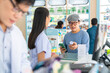 Medical pharmacy and healthcare providers concept. Professional Asian woman pharmacist recommend and selling medical product, medicine, drugs and supplements to male patient customer in drugstore.