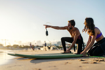 Wall Mural - A surf instructor is pointing at good wave while a girl smiling and watching.