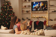 © New Africa - Mother with her children watching TV in cosy room. Christmas atmosphere
