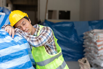 Construction worker with white safety helmet take a nap because so are tired from working in the hot sun on construction site, Sleeping during work, sleep at workplace, Over time employee. Copy Space