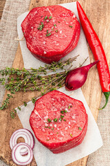 Wall Mural - Raw Eye of round steak with spices and herbs on wooden background. Fresh meat for cooking food