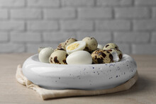 Unpeeled And Peeled Hard Boiled Quail Eggs In Bowl On White Wooden Table, Closeup