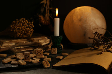 Canvas Print - Composition with wooden runes and old books on black table