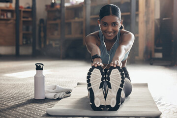 Wall Mural - Woman is stretching legs in gym, fitness and smile, start workout with earphones, portrait and sport preparation. Health, active with happy Indian female warm up and ready for exercise with music