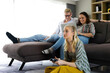 © NVB Stocker - Happy young family sitting on sofa and playing video game in living room at home.