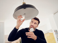 Man Changing Old Lightbulb For A LED Energy Saving Lightbulb