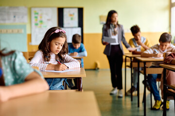 Wall Mural - Hispanic elementary student taking test during class in classroom.