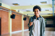 © Drazen - Happy black teenage boy in school hallway looking at camera.