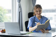 © crizzystudio - Confident female doctor, therapist sitting at desk with medical stethoscope Using a laptop and writing notes in a medical journal. planning ideas Study the treatment system, analyze life insurance.