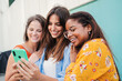 © Jose Calsina - Group of young women smiling and having fun using a cellphone. Three teenage females enjoying together browsing on internet with smartphone. Multiracial ladies laughing and watching videos with phone