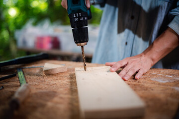 Hands of carpenter uses hand drill to assemble the wood in the wood studio at home