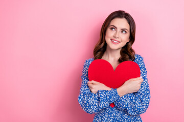 Poster - Portrait of charming cheerful minded lady arms hold hug paper heart card look empty space isolated on pink color background