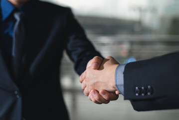 Business etiquette, congratulations, and merger and acquisition principles are demonstrated by a businessman shaking hands with his partner at the office.