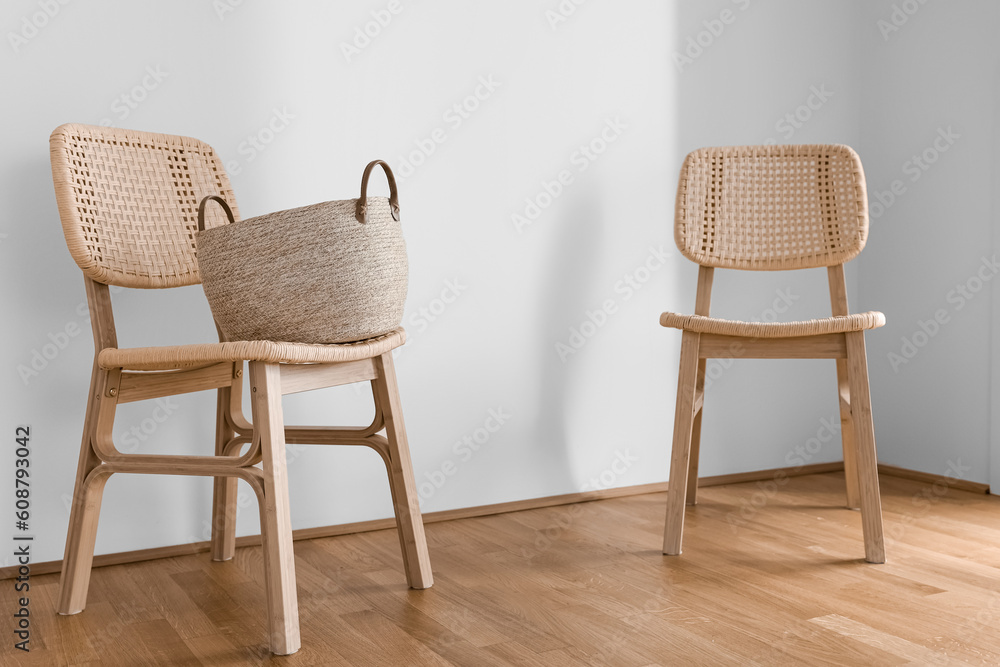Wicker chairs with basket near light wall